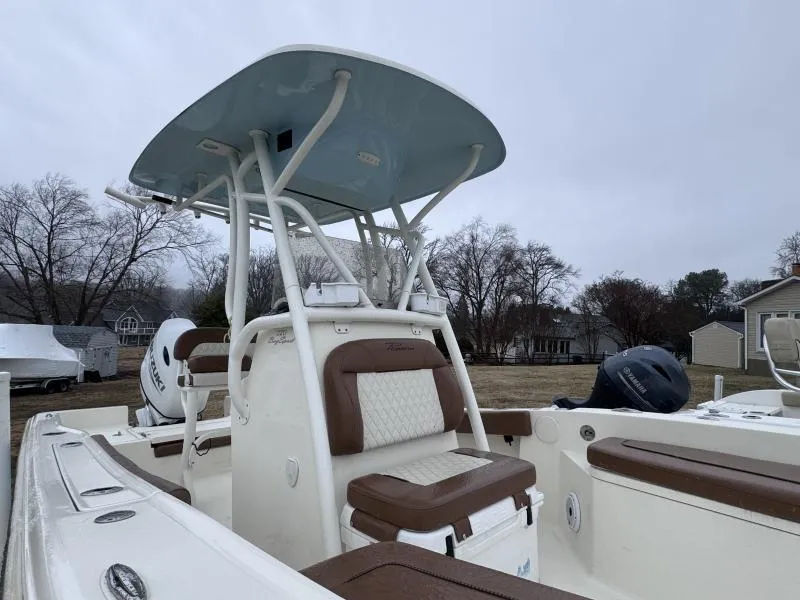 Slide: The Image of 2021 Pioneer 220 Bay Sport boat with T-top and seating, parked outdoors. - 12