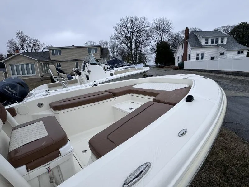 Slide: The Image of 2021 Pioneer 220 Bay Sport boat with brown seating, parked near residential homes. - 13