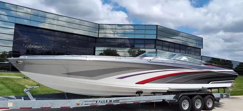 Slide: The Image of 2015 Formula 382 FASTech boat on trailer, parked near modern glass building under cloudy sky. - 1