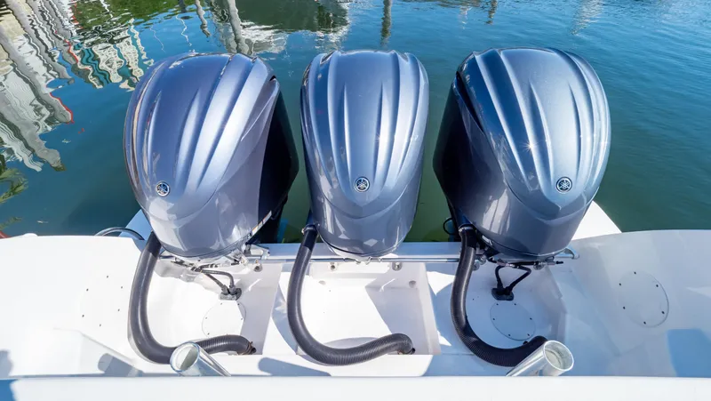 Slide: The Image of Triple outboard engines on a 2023 Intrepid 375 Nomad FE boat, docked on calm water. - 34