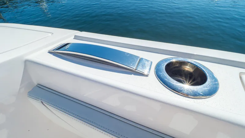 Slide: The Image of 2023 Intrepid 375 Nomad FE boat detail with chrome handle and cup holder by the water. - 47