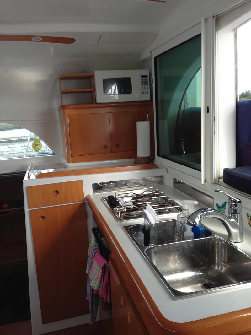 Slide: The Image of 2007 Lagoon 380 S2 yacht kitchen with sink, stove, and wooden cabinets. - 3