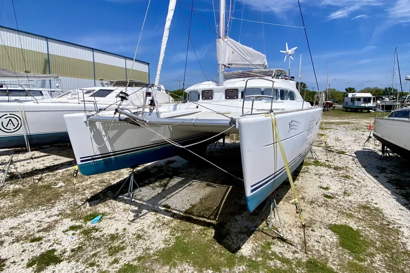 Slide: The Image of 2007 Lagoon 380 S2 catamaran on land, with sails and wind turbine, under clear blue sky. - 32