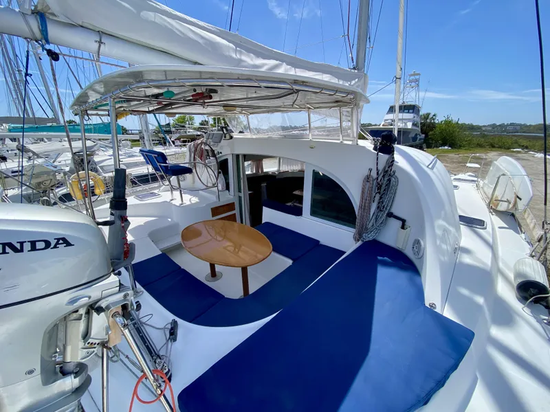Slide: The Image of 2007 Lagoon 380 S2 catamaran with blue seating and wooden table in the cockpit area. - 34