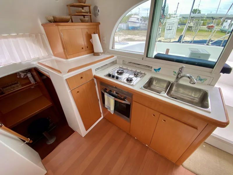 Slide: The Image of Compact kitchen in a 2007 Lagoon 380 S2 catamaran with stove, sink, and wooden cabinetry. - 8