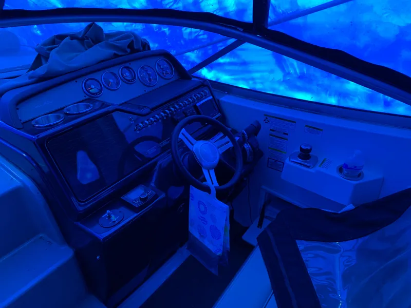 Slide: The Image of 2017 Sea Ray Sundancer 310 cockpit with blue lighting, featuring steering wheel and control panel. - 2