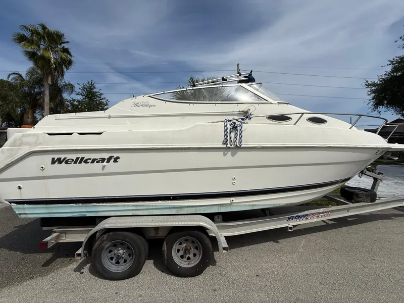 Slide: The Image of 2000 Wellcraft 2400 Martinique boat on trailer, parked outdoors under a cloudy sky. - 12