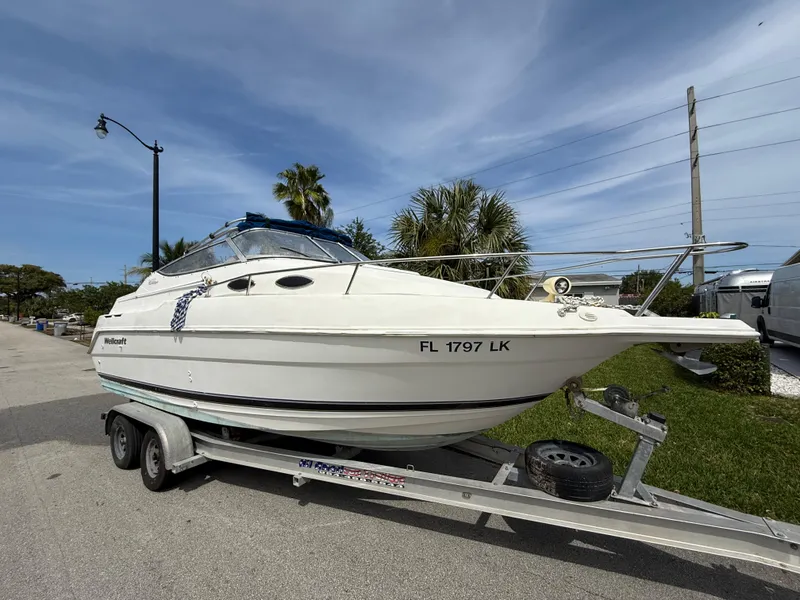 Slide: The Image of 2000 Wellcraft 2400 Martinique boat on trailer, parked on a sunny street. - 15