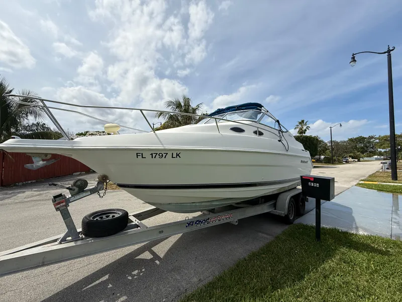 Slide: The Image of 2000 Wellcraft 2400 Martinique boat on trailer, parked outdoors under a cloudy sky. - 26