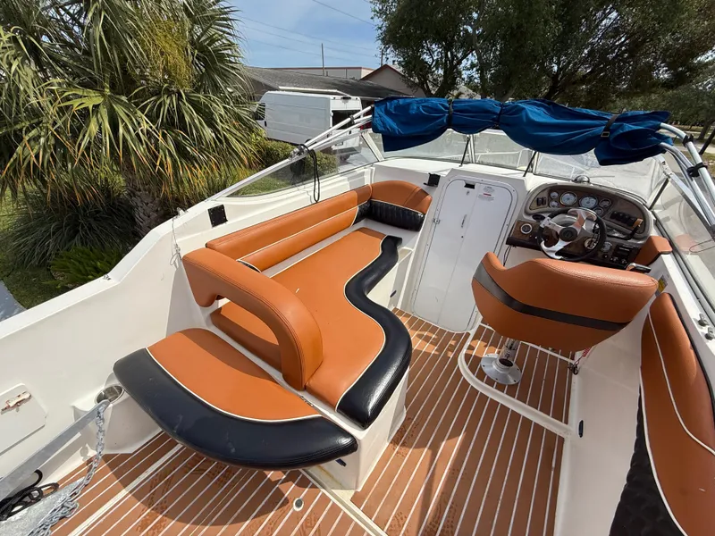 Slide: The Image of 2000 Wellcraft 2400 Martinique boat interior with tan and black seating, wooden flooring, and steering console. - 35
