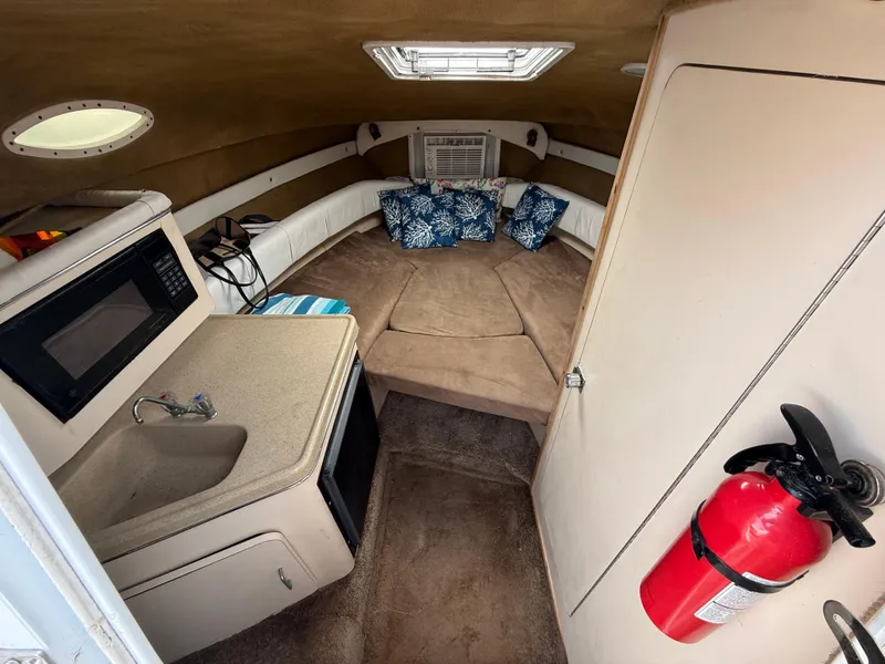 Slide: The Image of 2000 Wellcraft 2400 Martinique cabin interior with kitchenette, seating, and fire extinguisher. - 45