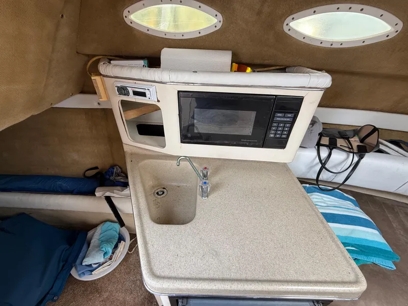Slide: The Image of 2000 Wellcraft 2400 Martinique boat interior with kitchenette, sink, and microwave. - 49