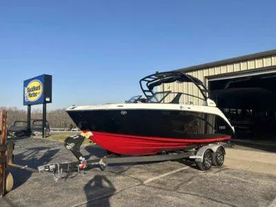 Slide: The Image of 2025 Yamaha Boats 222SD on trailer, parked outside a building under clear blue sky. - 2