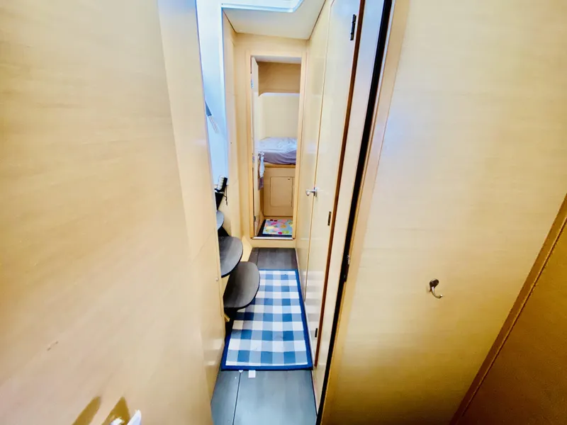 Slide: The Image of Narrow hallway inside 2014 Lagoon 380 S2 yacht with wooden interior and checkered rug. - 24