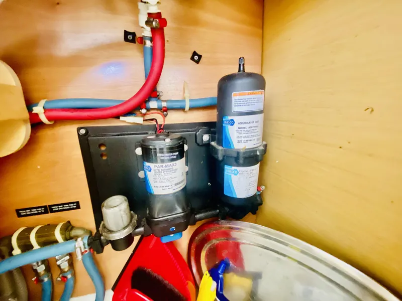 Slide: The Image of 2014 Lagoon 380 S2 yacht plumbing system with filters and pipes in a wooden compartment. - 47