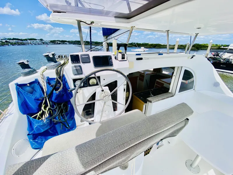 Slide: The Image of Helm of 2014 Lagoon 380 S2 catamaran with navigation equipment, docked by a scenic waterfront. - 7