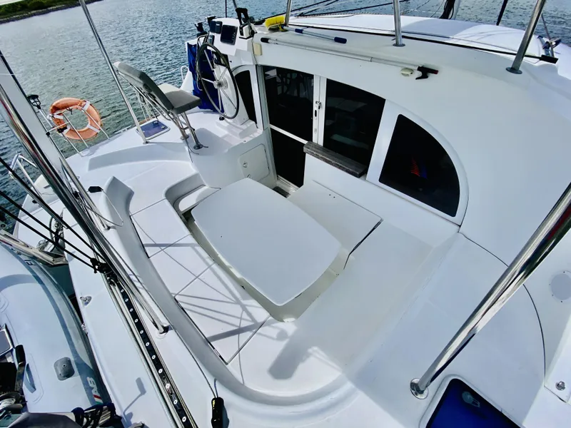 Slide: The Image of 2014 Lagoon 380 S2 catamaran cockpit with seating and helm, docked by the water. - 9