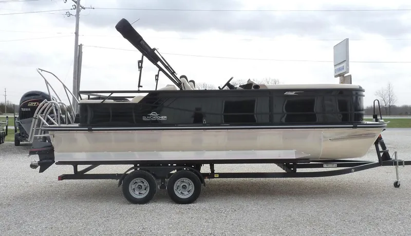Slide: The Image of 2025 SunCatcher Select 322SS pontoon boat on a trailer, parked outdoors. - 4