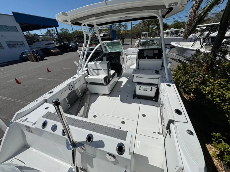 Slide: The Image of 2022 Blackfin 252 DC boat interior with seating and console, parked outdoors. - 23
