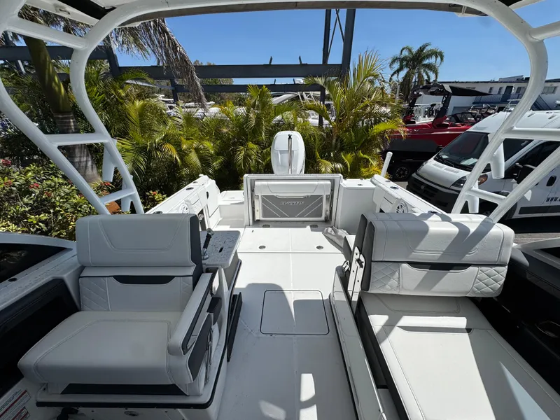Slide: The Image of 2022 Blackfin 252 DC boat interior with white seating and lush greenery background. - 44