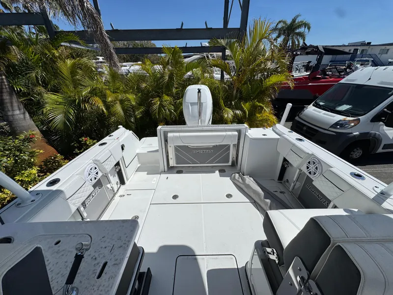 Slide: The Image of 2022 Blackfin 252 DC boat interior with seating, surrounded by tropical plants and parked vehicles. - 45