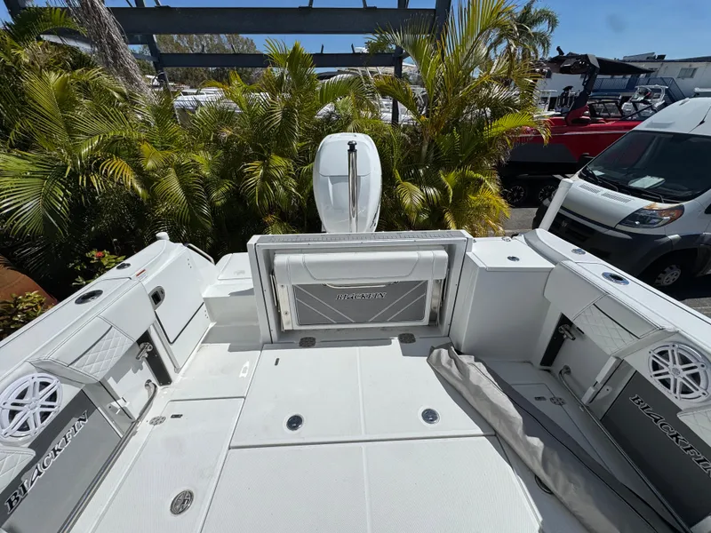 Slide: The Image of 2022 Blackfin 252 DC boat deck with seating, surrounded by lush greenery. - 46