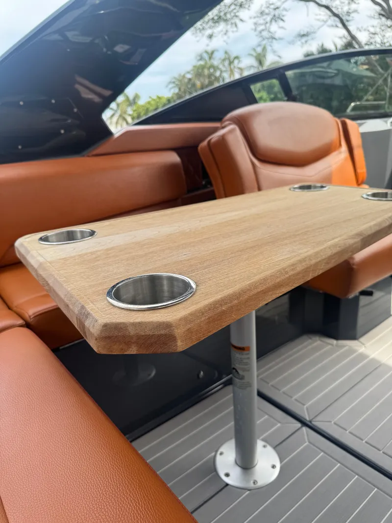 Slide: The Image of 2021 Cruisers Yachts 338 South Beach Edition Bow Rider interior with wooden table and cup holders. - 26