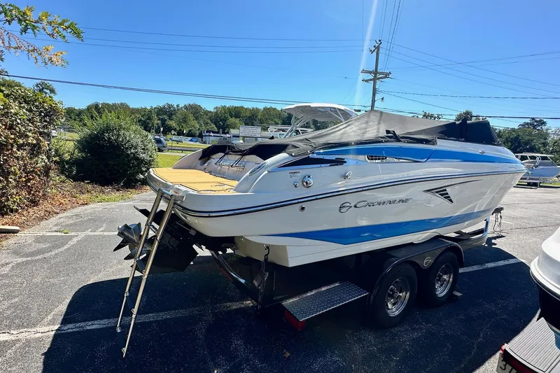 Slide: The Image of 2023 Crownline 240 SS boat on trailer, parked outdoors under clear blue sky. - 1