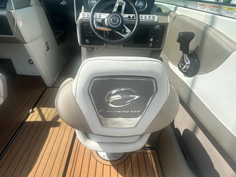 Slide: The Image of 2023 Crownline 240 SS boat interior with steering wheel and branded seat on wooden deck. - 26