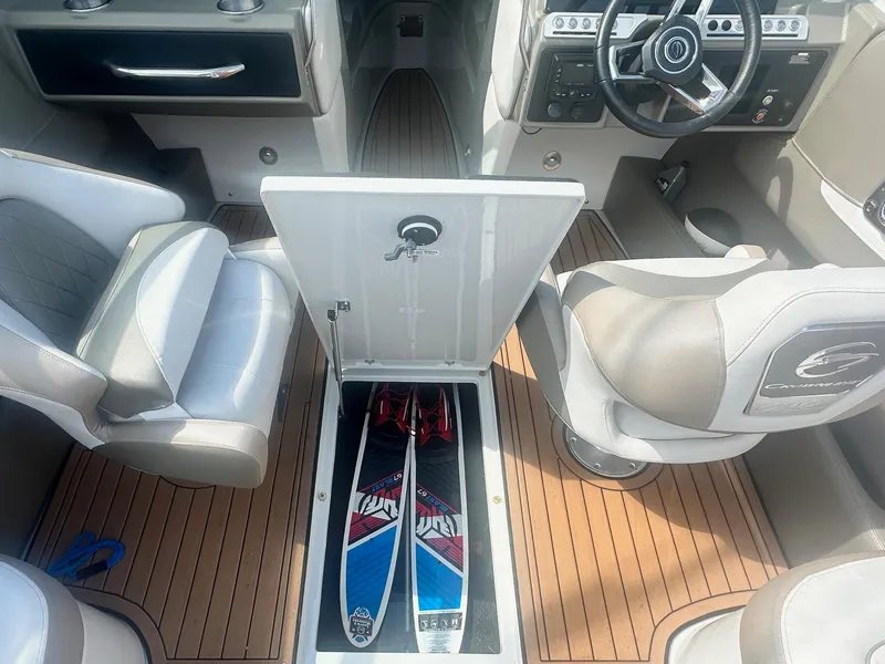 Slide: The Image of 2023 Crownline 240 SS boat interior with open storage compartment and water skis. - 28