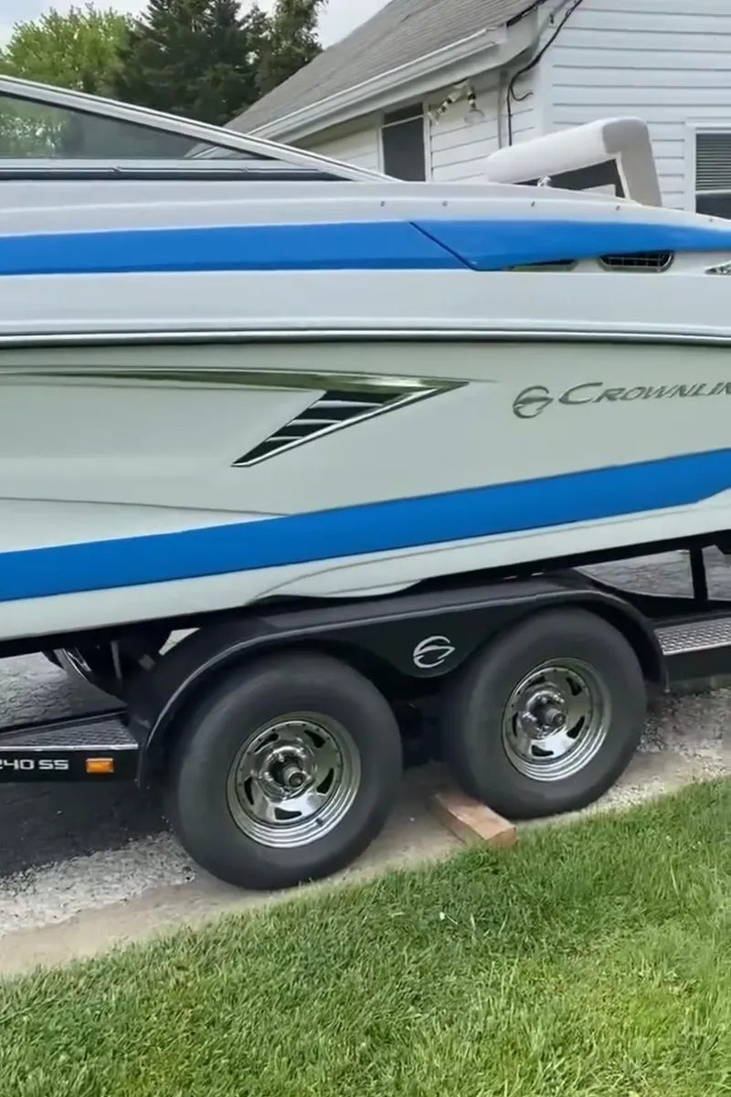 Slide: The Image of 2023 Crownline 240 SS boat on trailer, featuring sleek blue and white design. - 5