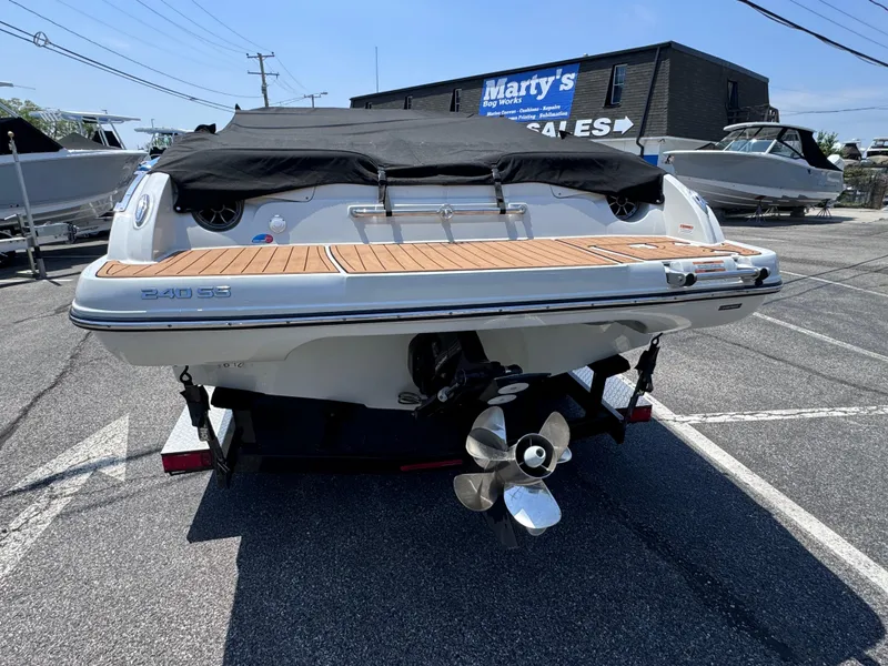 Slide: The Image of 2023 Crownline 240 SS boat with covered deck, displayed at a sales lot. - 6