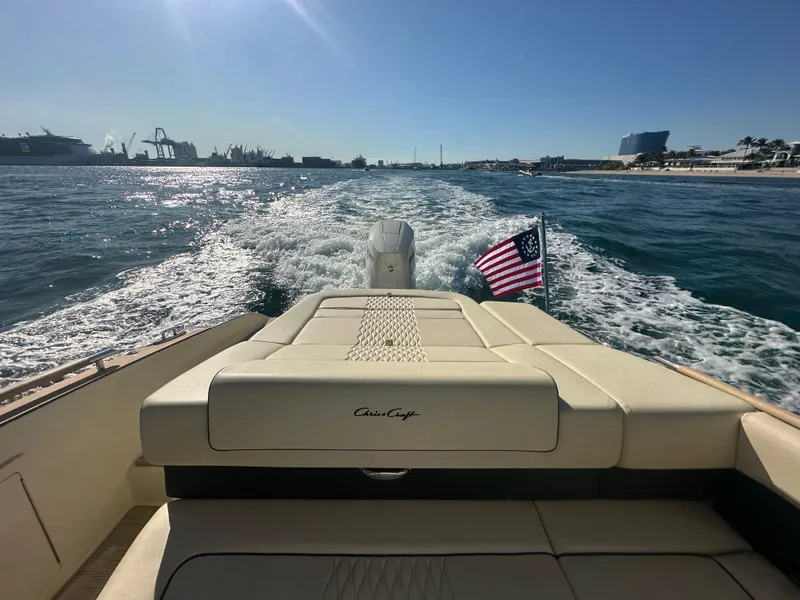 Slide: The Image of 2025 Chris-Craft Sportster 28 cruising on open water, American flag waving, sunny day. - 4