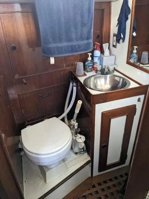 Slide: The Image of 1981 Kelly Peterson 44 yacht bathroom with wooden cabinetry, toilet, and stainless steel sink. - 10