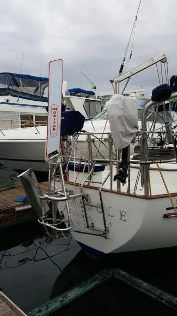 Slide: The Image of 1981 Kelly Peterson 44 sailboat docked, featuring a wind vane and covered equipment. - 14