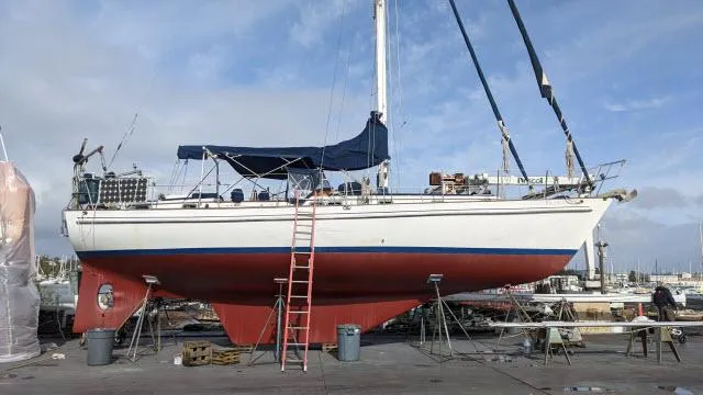 Slide: The Image of 1981 Kelly Peterson 44 sailboat on dry dock with red hull and blue canopy. - 18