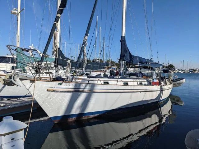 Slide: The Image of 1981 Kelly Peterson 44 sailboat docked in a marina, reflecting on calm water. - 24