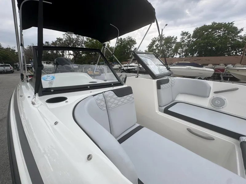 Slide: The Image of 2025 Bayliner Element M17 boat interior with seating and canopy, parked outdoors. - 4