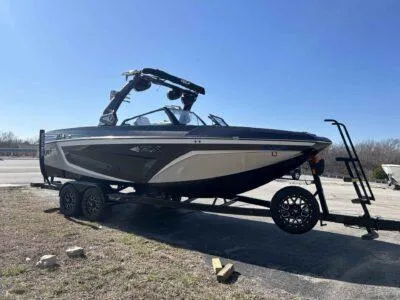 Slide: The Image of 2021 Tigé 23ZX boat on trailer under clear blue sky. - 1