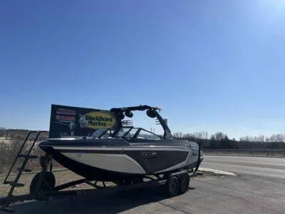 Slide: The Image of 2021 Tigé 23ZX boat on trailer under clear blue sky. - 2