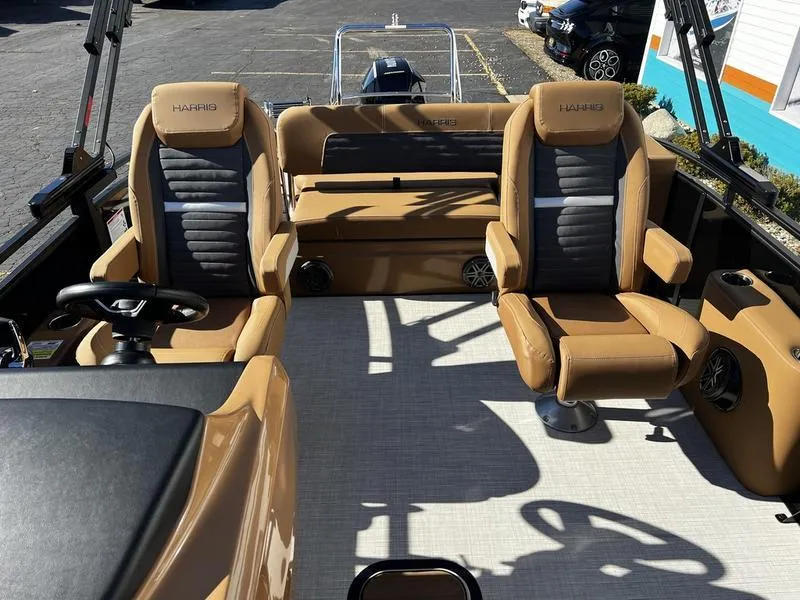 Slide: The Image of 2024 Harris Solstice 230 boat interior with tan and gray seating, steering wheel, and spacious layout. - 12