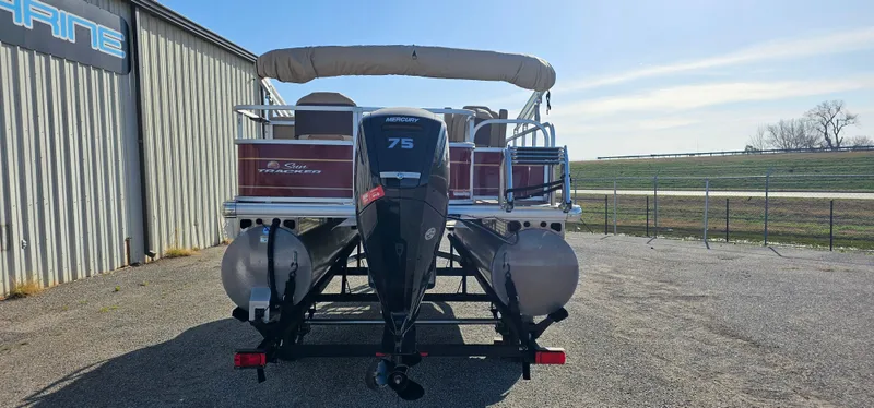 Slide: The Image of 2024 Sun Tracker BB-18 pontoon boat with 75 HP engine, parked outdoors. - 3