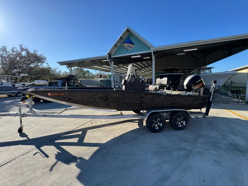Slide: The Image of 2023 Xpress H22B boat on trailer, parked outside a marina under clear skies. - 1