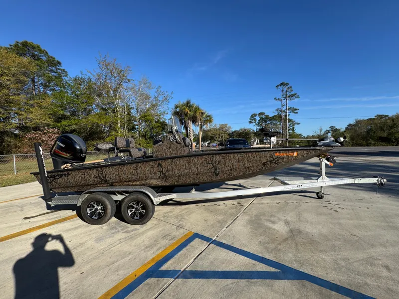 Slide: The Image of 2023 Xpress H22B boat on trailer in parking lot, surrounded by trees. - 10