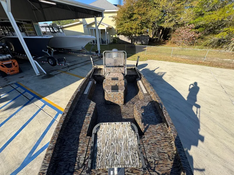 Slide: The Image of 2023 Xpress H22B boat with camouflage design, parked outdoors near other boats. - 22