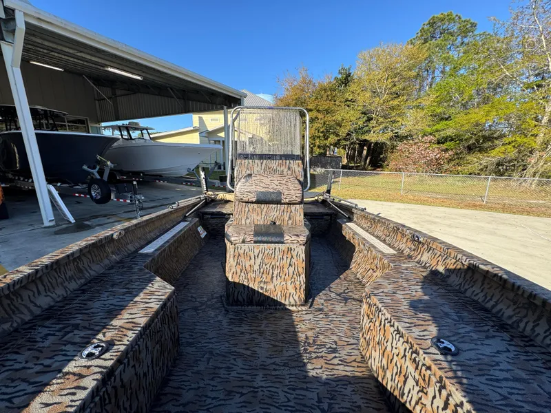 Slide: The Image of 2023 Xpress H22B boat with camouflage interior, parked outdoors under clear blue sky. - 23