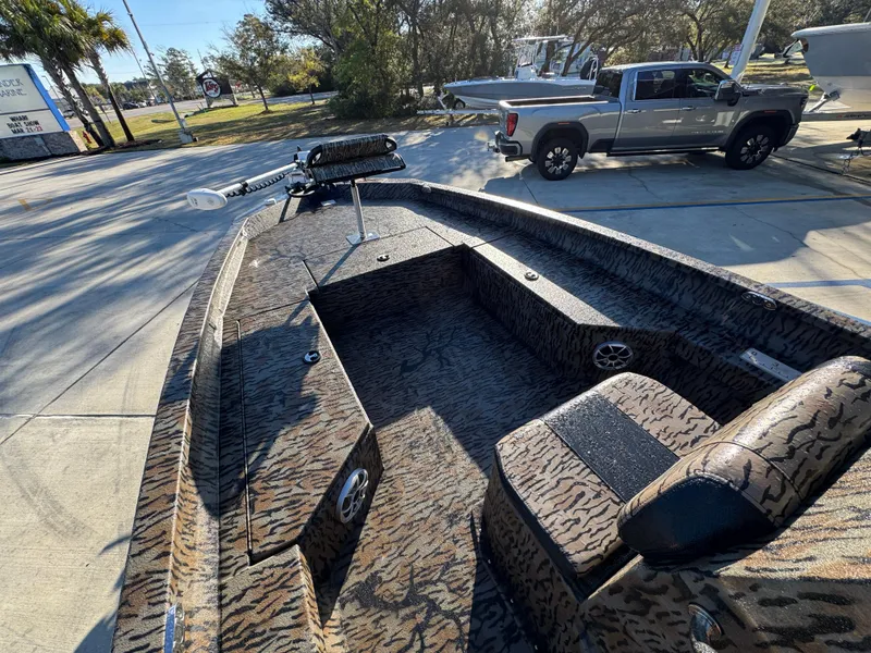 Slide: The Image of 2023 Xpress H22B boat with camo interior, parked near a pickup truck. - 24