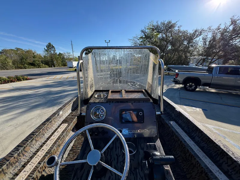 Slide: The Image of 2023 Xpress H22B boat interior with steering wheel and dashboard, parked outdoors. - 31