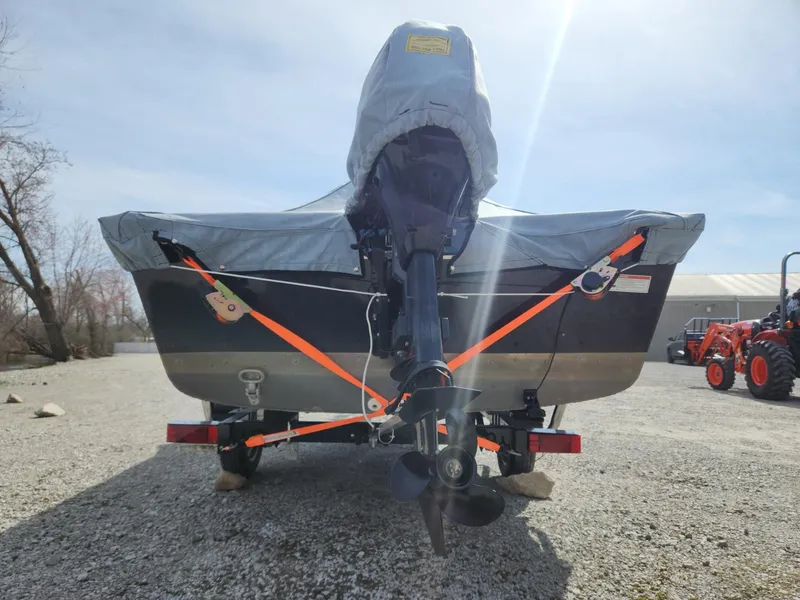 Slide: The Image of 2021 Starcraft 16 SF DLX boat, covered and secured, parked on gravel. - 16