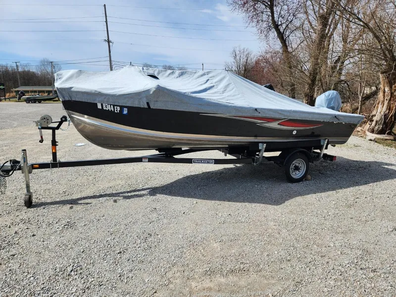 Slide: The Image of 2021 Starcraft 16 SF DLX boat on trailer, covered, parked on gravel. - 2